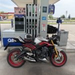 Moto sportiva parcheggiata a un distributore di benzina Q8, con casco sul sellino