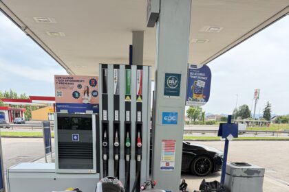 Moto sportiva parcheggiata a un distributore di benzina Q8, con casco sul sellino