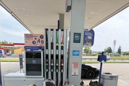Moto sportiva parcheggiata a un distributore di benzina Q8, con casco sul sellino