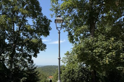 Moto sportiva parcheggiata con casco su un belvedere alberato, con vista panoramica sullo sfondo